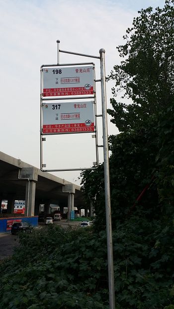 '山莊東大門口的公交站牌，背景為在建的新107國道高架橋'