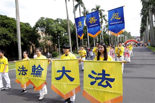 '圖2：法輪大法社以燦爛的「法輪大法」金色橫幅為前導，為遊行帶來蓬勃的氣象。'