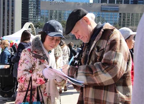 '圖7：了解真相的民眾在徵簽表上簽名，制止迫害法輪功。'