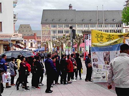 '圖2：中國旅遊團的遊客路過法輪功真相點時，遊客駐足閱讀展板。'