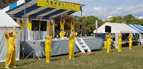 '圖1：二零一九年十月二十七日，法輪功學員在廣島和平與友愛國際交流節的舞台上演示法輪功五套功法動作。'