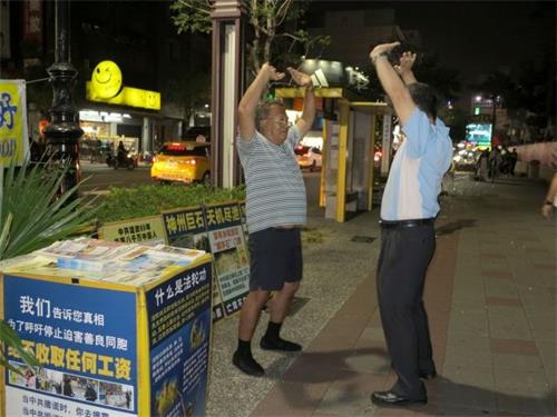 '圖4：瑞豐夜市上遊客學煉法輪功'