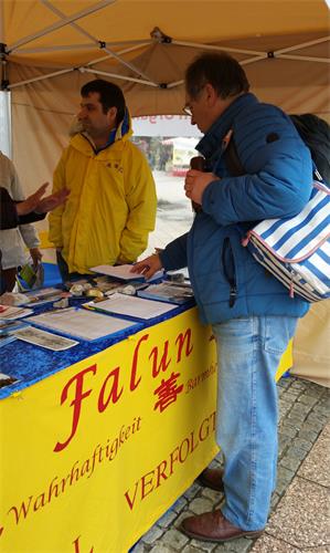 圖7：來自德國Karlsruhe的Bley先生，看到信息台上放著《轉法輪》，拿起來翻看了一下目錄，裏面的話題立時引起他極大興趣，於是當即買了書。