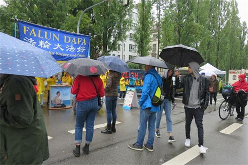 '圖5：法輪功學員在雨中堅持煉功，吸引了民眾觀看'