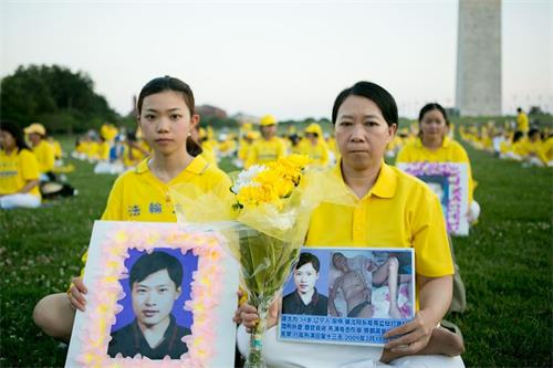 '圖5：二零二一年七月十六日晚，一千多名法輪功學員在美國首都華盛頓DC舉辦燭光悼念。圖為遲麗華（右）和女兒徐鑫洋手捧丈夫徐大為的遺像。'