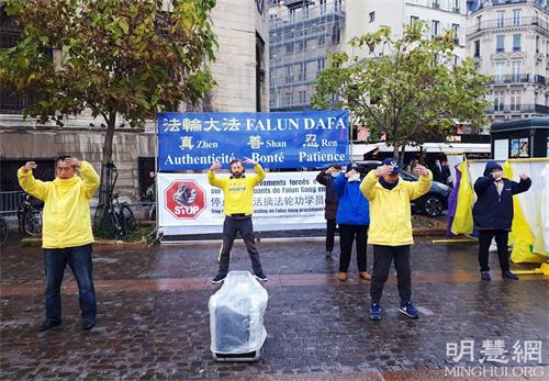 '圖4：二零二一年十一月十三日，在夏特蕾地鐵站外，法輪功學員展示法輪功功法。'