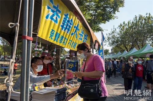 '圖3：路竹蕃茄節設有法輪功展位，不斷有民眾前來拿取法輪功資料和寫有九字真言「法輪大法好 真善忍好」的小蓮花飾品。'