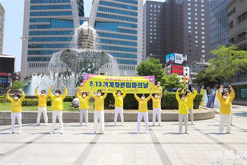 圖2：5月13日，部份首爾西部和中部的法輪功學員們在首爾市中心新世界百貨店附近的大型噴泉前舉行了集體煉功、派發傳單等洪法活動。圖為他們在集體煉功的場面。