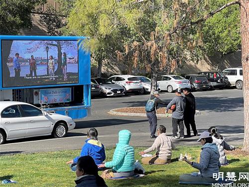 '圖1：在坎貝爾公園 ，遊人觀看真相車播放介紹法輪大法的視頻，並接受法輪功學員給的真相資料'