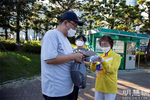 '圖3：釜山法輪功學員向來往市民講真相與發送真相特刊。'