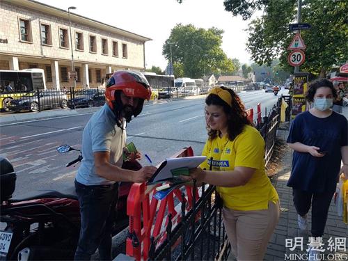 '圖9：一位騎摩托車的男士停下來在要求解體中共的請願信上簽字'