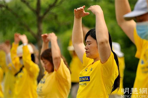 '圖1：在法輪功學員反迫害22週年之際，原南京鳳凰街法輪功煉功點輔導員李娥英在加拿大中使館前參加反迫害集會，集體煉功。'