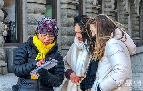 '圖5：兩位來自德國年輕的姑娘頂著寒風很專注地在聽學員講真相。簽名讓她們感到很榮幸，她們認為「迫害很可怕，但沉默比迫害更恐怖！」'