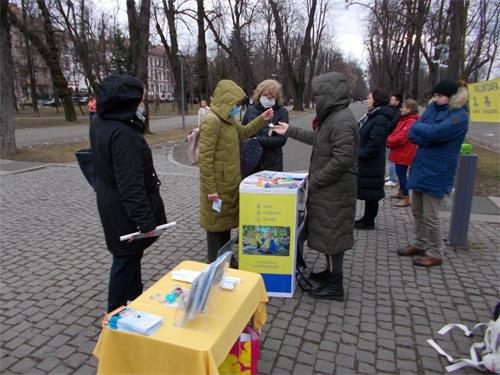 '圖13：路人在克盧日中央公園接過真相小蓮花和法輪功受迫害的真相信息'