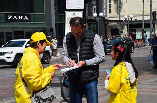 圖3：法輪功學員和路人講真相後，路人在呼籲結束中共迫害法輪功的請願書上簽名。