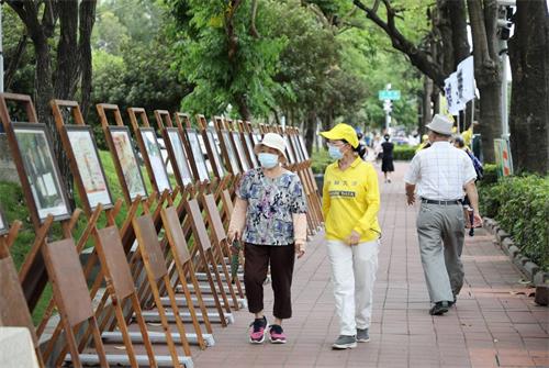 圖3: 李姓學員陪著對大法有誤解的老太太，邊走邊看展板，經過學員細心講真相之後，老太太心中豁然開朗，解開心中的誤解。