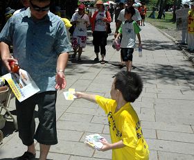 七月十八日屏東學員在鵝鑾鼻講真相，圖為小弟子分送真相材料給行人