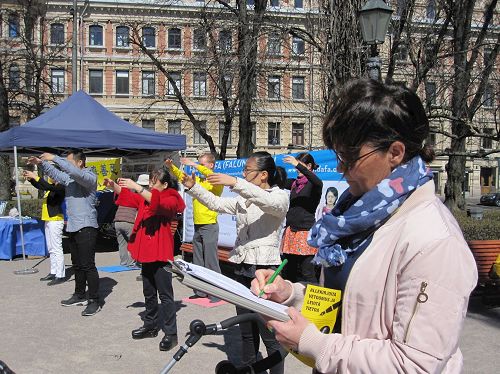 '圖2：法輪功學員正在向民眾展示法輪功功法，分享法輪大法的美好。'