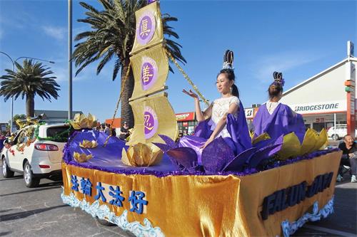 '圖3：仙女打扮的學員在花車上展示法輪功功法'