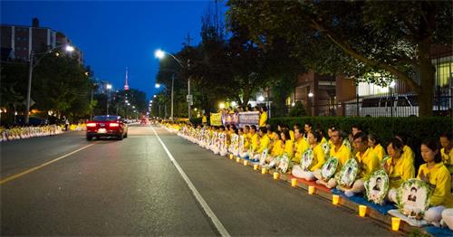 '圖1～3：夜幕漸漸降臨，法輪功學員安靜祥和肅穆的場面，吸引不少來往民眾駐足關注和了解真相。有過往的車輛慢慢停下來錄像，有司機詢問要資料，許多路人紛紛用手機記錄，並支持法輪功學員反迫害，還有大陸民眾現場三退。'