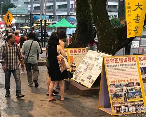 '圖2～4：遊客駐足看展板、聽真相。'